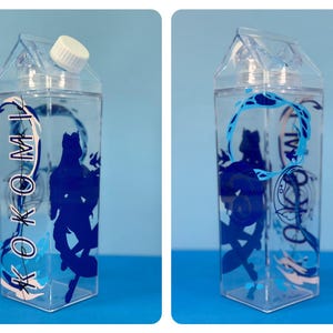 May include: Clear plastic water bottle with a white cap, shaped like a milk carton. The bottle features a blue silhouette design of a figure and the word "KOKOMI" in a stylized font. The bottle is filled with clear liquid.