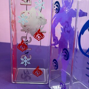May include: Clear, rectangular water bottles with character designs. One bottle features red flame and blue snowflake graphics, while another displays a purple character silhouette. The bottles are made of clear plastic.