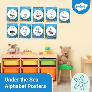 Puede incluir: Carteles educativos del alfabeto con criaturas marinas como el caimán, el pez globo y el pez payaso. Cada tarjeta muestra una letra y una ilustración de animal. Los carteles están sobre una unidad de almacenamiento de madera con contenedores coloridos, juguetes y un oso de peluche.