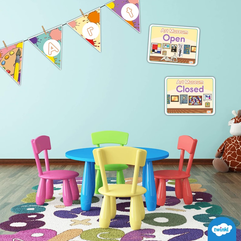 Puede incluir: Una colorida sala de juegos con una mesa azul y cuatro sillas rosas, amarillas, verdes y rojas. La habitaci&oacute;n tiene una alfombra con letras y n&uacute;meros, banderines tem&aacute;ticos de arte y letreros de "Museo de Arte Abierto/Cerrado".