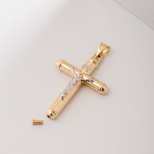 Könnte beinhalten: Vergoldeter Kreuzanhänger mit silberfarbener Jesusfigur. Das Kreuz hat ein zylindrisches Design mit einer kleinen Schraube und den Buchstaben INRI. Ein religiöses Schmuckstück.