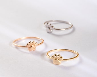 Puede incluir: Tres anillos de plata con un diseño de huella de pata. Los anillos están apilados uno encima del otro, con el anillo más grande en la parte inferior y el anillo más pequeño en la parte superior.