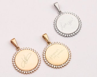 May include: Three gold and silver pendants with a circle design and a border of small clear stones. The pendants have different engravings: "Love you!" on the silver pendant, "Forever Mama" on the gold pendant, and a handwritten signature on the other gold pendant.