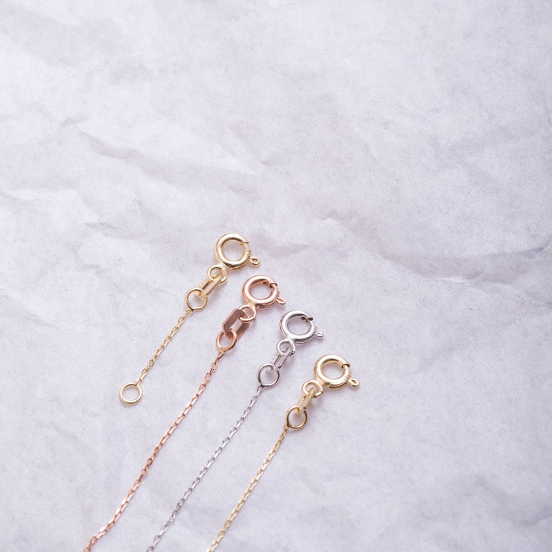 May include: Four gold chains with different clasps. The chains are in yellow gold, rose gold, and white gold.