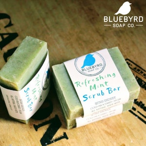 May include: Two bars of green soap with a white label that reads "Refreshing Mint Scrub Bar" and "Bluebyrd Soap Co."