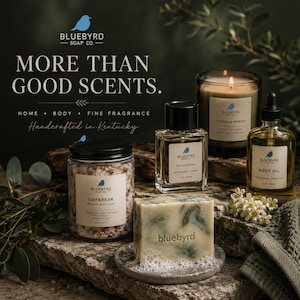 May include: A collection of Bluebyrd Soap Co. products including a jar of Daybreak mineral bath soak, a bottle of eau de parfum, a scented candle, a bottle of body oil, and a bar of soap with the word bluebyrd embossed on the front surface.