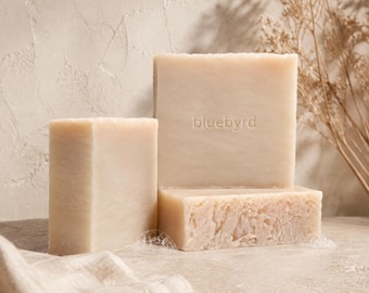 May include: Three rectangular bars of light beige soap arranged in a stack. The largest upright bar features the embossed text bluebyrd in the center. The soap has a smooth surface with a slightly textured, uneven bottom edge on the base bar.