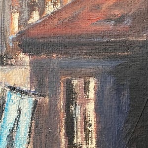 May include: A painting of a building with a red roof and a window. The building is painted in shades of brown, black, and blue. There is a blue object hanging in the foreground.