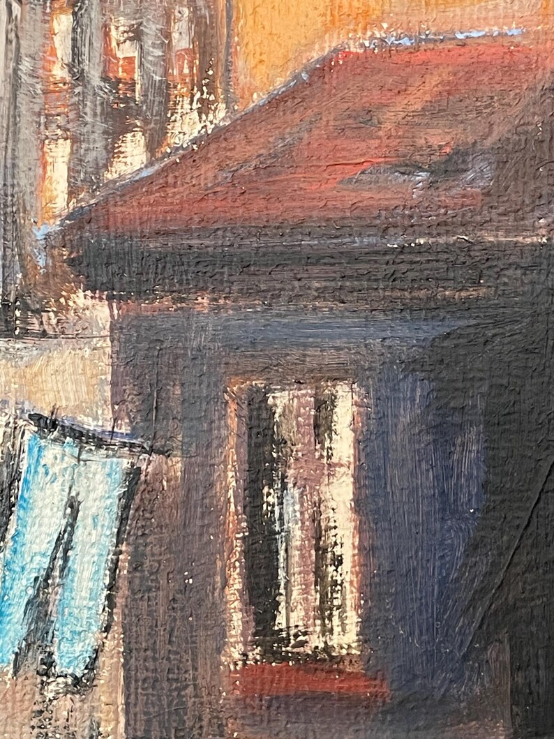 May include: A painting of a building with a red roof and a window. The building is painted in shades of brown, black, and blue. There is a blue object hanging in the foreground.
