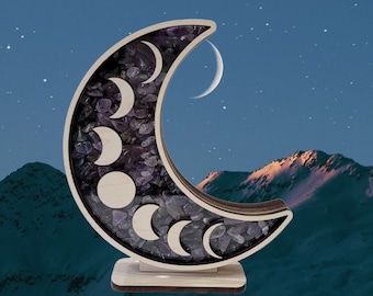 May include: Wooden crescent moon sculpture with amethyst crystals embedded in the design. The moon phases are carved into the wood and the sculpture is on a wooden base.