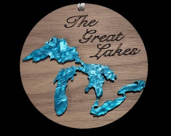 May include: A round wooden ornament with a blue outline of the Great Lakes and the text "The Great Lakes" in black lettering.