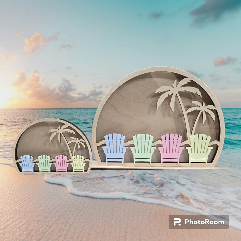 Op de afbeelding: Een houten uitsnijding van een strandsc&egrave;ne met palmbomen en vijf kleurrijke Adirondack-stoelen. De uitsnijding bevindt zich op een wit zandstrand met blauwe oceaan op de achtergrond.