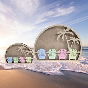 Op de afbeelding: Twee houten wanddecoraties in de vorm van een halve cirkel met een strandscene. Het grotere stuk heeft vier uitgesneden stoelen in blauw, groen, roze en geel. Het kleinere stuk heeft vier uitgesneden stoelen in blauw, groen, roze en geel. Beide stukken hebben uitgesneden palmbomen.