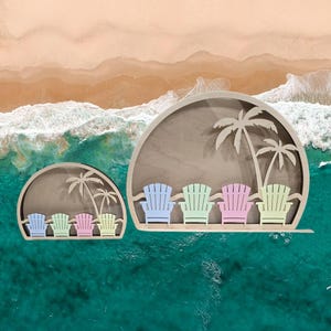 Op de afbeelding: Twee houten wanddecoraties met een strandsc&egrave;ne met palmbomen en Adirondack-stoelen. Het grotere stuk heeft vier stoelen in blauw, groen, roze en geel. Het kleinere stuk heeft drie stoelen in blauw, groen en roze.