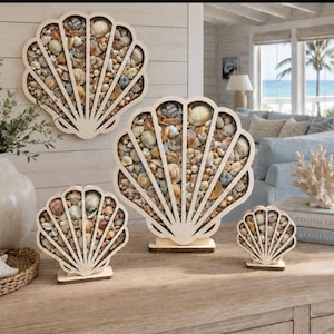 May include: A collection of seashell-filled, wooden shell-shaped wall art and tabletop decor. The pieces vary in size and are filled with a variety of seashells and small stones. The wooden frames are light-colored, and the overall theme is coastal and nautical.