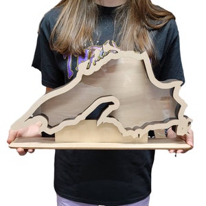 May include: A wooden cutout of the state of Michigan with a clear acrylic insert. The cutout is standing on a wooden base.