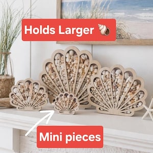 May include: Three light-colored wooden shell-shaped display cases filled with various small seashells. The display cases are in three different sizes. The image includes red rectangular text boxes with the white text Holds Larger and Mini pieces with a white arrow pointing to the smallest shell case.