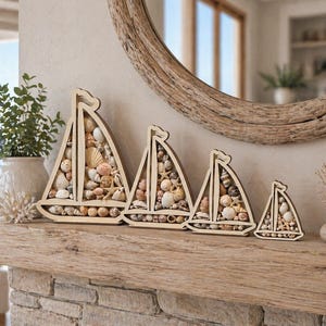 May include: Four wooden sailboat decorations filled with seashells of various shapes and colors. The sailboats are arranged in a row on a wooden mantel, with a mirror and greenery in the background. The sailboats vary in size.