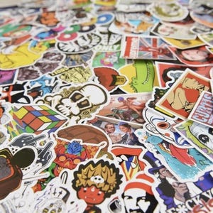 May include: A collection of colorful stickers with various designs, including skulls, cartoon characters, and pop culture references. The stickers are of different shapes and sizes, with a variety of colors and images. Some stickers have text, and others feature illustrations.