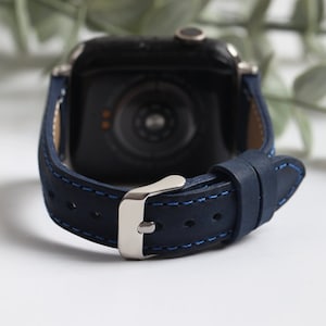 Op de afbeelding: Een donkerblauw leren horlogebandje met een zilveren gesp en blauwe stiksels. Het bandje is ontworpen voor een smartwatch.