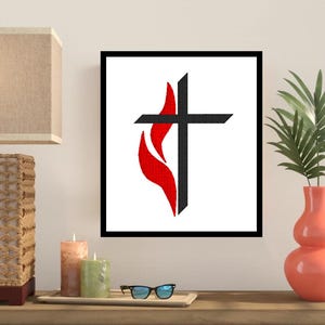 May include: A framed print of a black cross with a red flame behind it. The cross and flame are stylised and are on a white background.