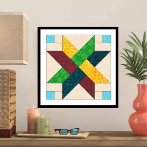 May include: A framed quilt block featuring a star design. The star is composed of various patterned fabrics in shades of green, yellow, burgundy, and blue, set against a neutral background. The quilt block is framed in black and displayed on a wooden surface.