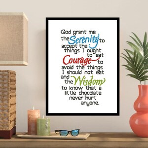 May include: A framed print with the text "God grant me the Serenity to accept the things I ought to eat, Courage to avoid the things I should not eat, and the Wisdom to know that a little chocolate never hurt anyone." The text is in various colors.