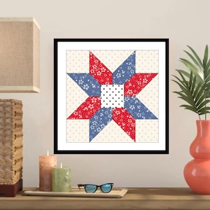 May include: Framed quilt block featuring a star design. The star is composed of red and blue floral patterned fabric, with a white and black polka dot center. The background is a cream color with small pink polka dots.