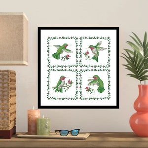 May include: A framed cross-stitch design featuring four green hummingbirds with pink flowers on a white background. The hummingbirds are in different poses, some flying and some perched on branches.