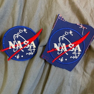 May include: Two blue and red NASA patches with white stars and the word "NASA" in white lettering.