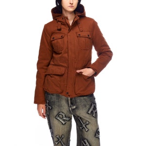 May include: A brown hooded jacket with a zipper closure and multiple pockets. The jacket has a quilted lining and a relaxed fit.