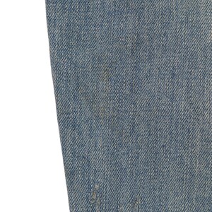 May include: Close-up of blue denim fabric with a distressed look. The fabric has a subtle texture and a faded appearance.