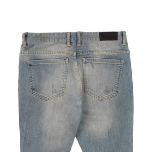 May include: A pair of light blue denim jeans with distressed details and a black leather patch on the back.