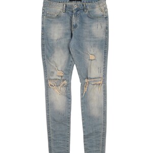 May include: Light blue distressed denim jeans with several rips and tears throughout the legs.