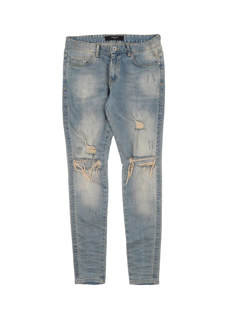 May include: Light blue distressed denim jeans with several rips and tears throughout the legs.
