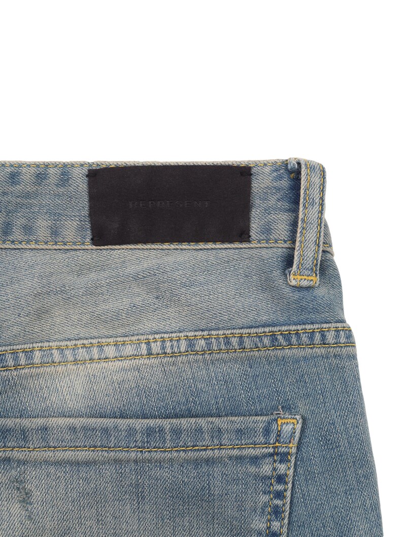 May include: A pair of blue denim jeans with a black leather patch that says "REPRESENT" on the back waistband.