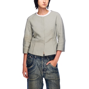 Puede incluir: Una chaqueta corta con estampado de lunares en blanco y negro y cuello redondo. La chaqueta se lleva sobre una camiseta blanca y unos vaqueros azules.