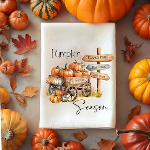 May include: A white rectangular kitchen towel with a fall theme. The towel features a wooden cart filled with pumpkins, the words "Pumpkin Season," and directional signs for a pumpkin patch, hay rides, and corn maze. Pumpkins and fall leaves surround the towel.