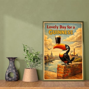 Peut inclure: Affiche encadr&eacute;e de style vintage avec un toucan tenant un verre de Guinness. Le texte "Lovely Day for a Guinness" est au-dessus. L'arri&egrave;re-plan montre une ville et un ciel nuageux, avec un mur de briques.