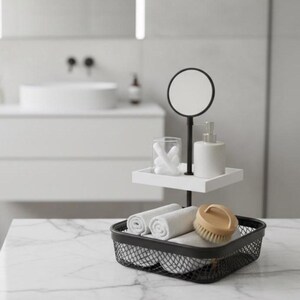Könnte beinhalten: Ein moderner Badezimmer-Organizer mit schwarzem Metallrahmen. Er verfügt über einen kleinen Spiegel, ein weißes Tablett mit Wattestäbchen und einen Seifenspender sowie einen unteren Korb mit gerollten weißen Handtüchern und einer Holzbürste.