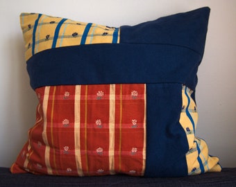 Könnte beinhalten: Ein Patchwork-Kissen mit einem blau-gelb-roten Streifenmuster. Das Kissen ist aus verschiedenen Stoffen gefertigt und hat eine quadratische Form.