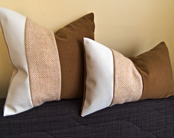 May include: Two decorative throw pillows with brown, beige, and white fabric. The pillows are rectangular and have a herringbone pattern.