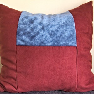 Peut inclure: Un coussin de décoration de couleur bordeaux et bleu avec un motif géométrique. Le coussin est fait d'un tissu doux et texturé.