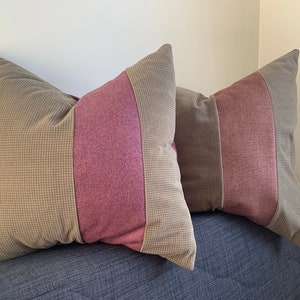 Peut inclure: Deux coussins décoratifs avec un motif à carreaux brun et rose. Les coussins sont sur un canapé bleu.