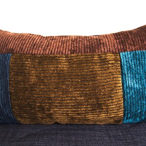 May include: A decorative pillow with a corduroy texture in shades of brown, gold and blue.