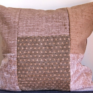 Può includere: Un cuscino rettangolare in patchwork di colore beige e marrone. Il cuscino è composto da diversi tessuti con motivi diversi.