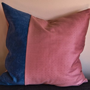 May include: A decorative cushion with a blue and pink fabric design. The cushion is made of two different fabrics, one with a smooth texture and the other with a textured surface.