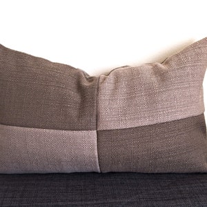 Peut inclure: Un coussin de décoration brun et beige avec un motif géométrique. Le coussin est fait d'un tissu texturé et a une forme carrée.