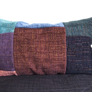 Peut inclure: Un oreiller patchwork multicolore avec un motif brun, bleu sarcelle, violet et bleu. L'oreiller est fait d'un tissu doux et texturé.