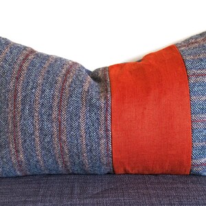 May include: A blue and red striped throw pillow with a large orange stripe down the centre.